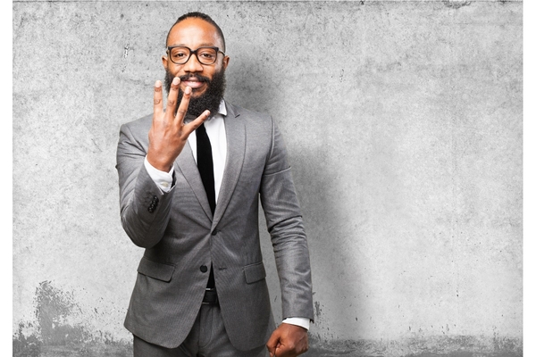 Man in suit and glasses holding up 4 fingers