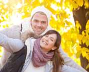 Couple posing in front of fall leaves