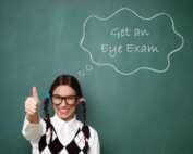 Girl with glasses and pigtails giving a thumbs up in front of a chalkboard that has 