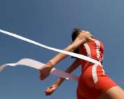 A competitive runner crossing the ribbon at the finish line