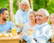 Elderly man seated at a dinner table with family